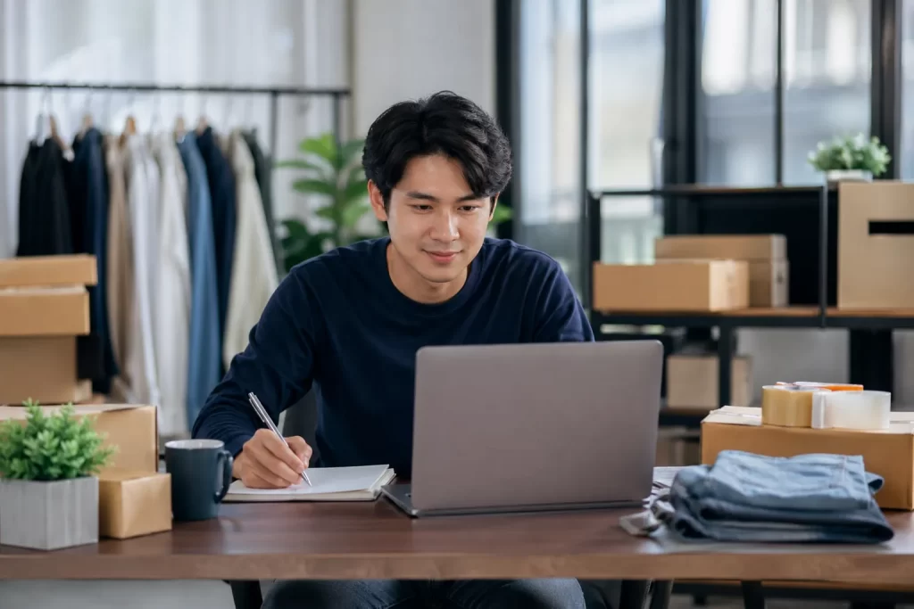 Een jonge ondernemer werkt vanuit een moderne werkplek aan zijn webshop en bestellingen.